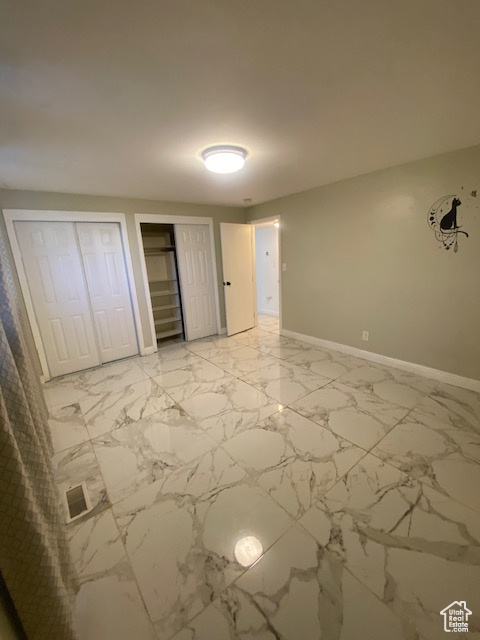 Unfurnished bedroom featuring multiple closets and light marble finish flooring