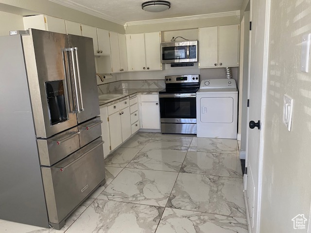 Kitchen with appliances with stainless steel finishes, washer / clothes dryer, crown molding, light marble finish flooring, and light countertops