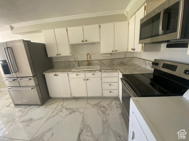 Kitchen featuring stainless steel appliances, crown molding, light countertops, light marble finish flooring, and white cabinets