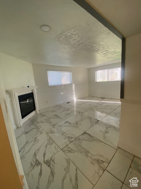 Unfurnished living room with a glass covered fireplace and light marble finish flooring
