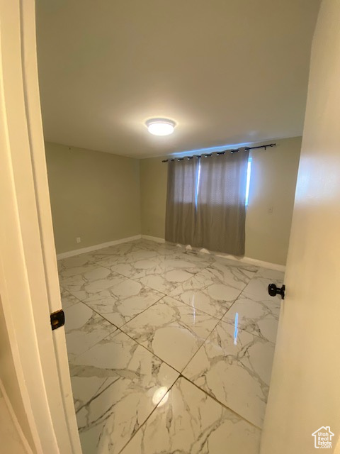 Spare room featuring baseboards and marble finish floors
