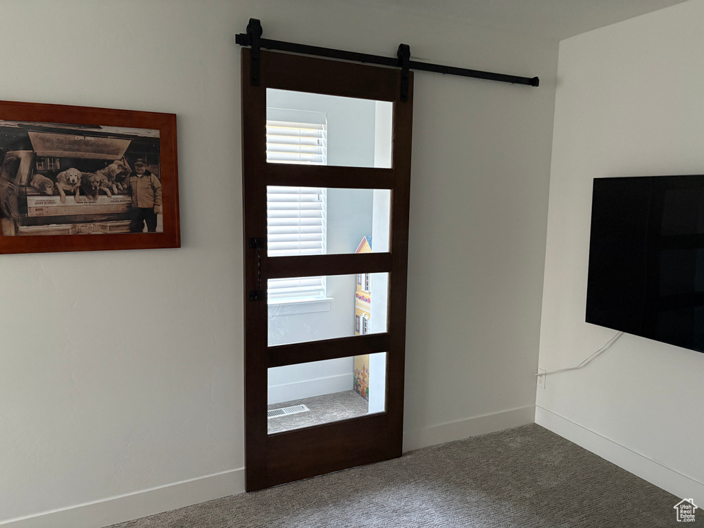 Carpeted entryway featuring a barn door and baseboards