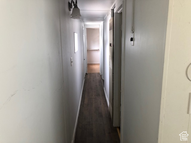 Hallway featuring dark wood-style flooring and baseboards