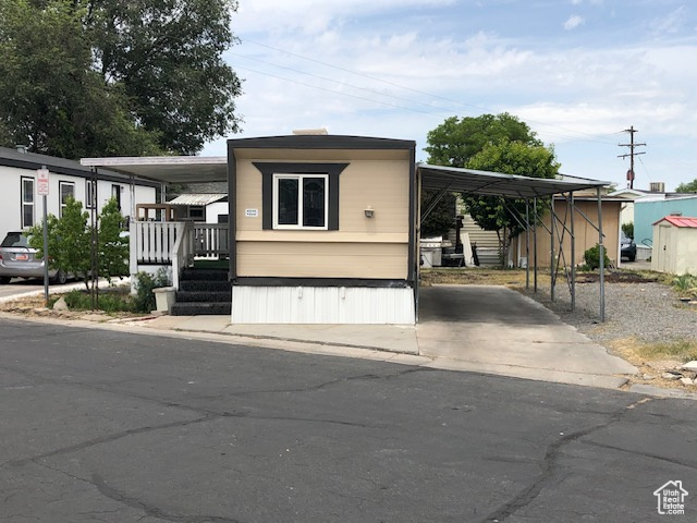 Manufactured / mobile home with a carport, driveway, and covered porch