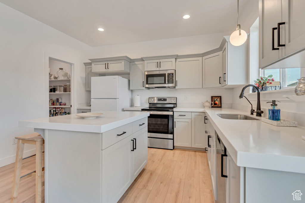 Kitchen featuring stainless steel appliances, a center island, light wood-type flooring, light countertops, and recessed lighting