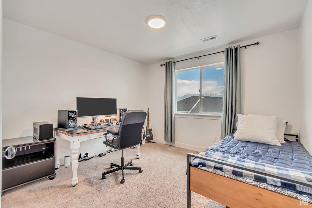 Carpeted bedroom featuring an office area and baseboards