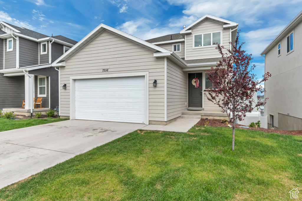 Traditional home with an attached garage, a front lawn, driveway, and roof with shingles
