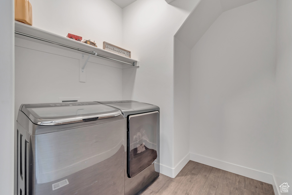 Laundry area with washing machine and dryer and light wood-style flooring