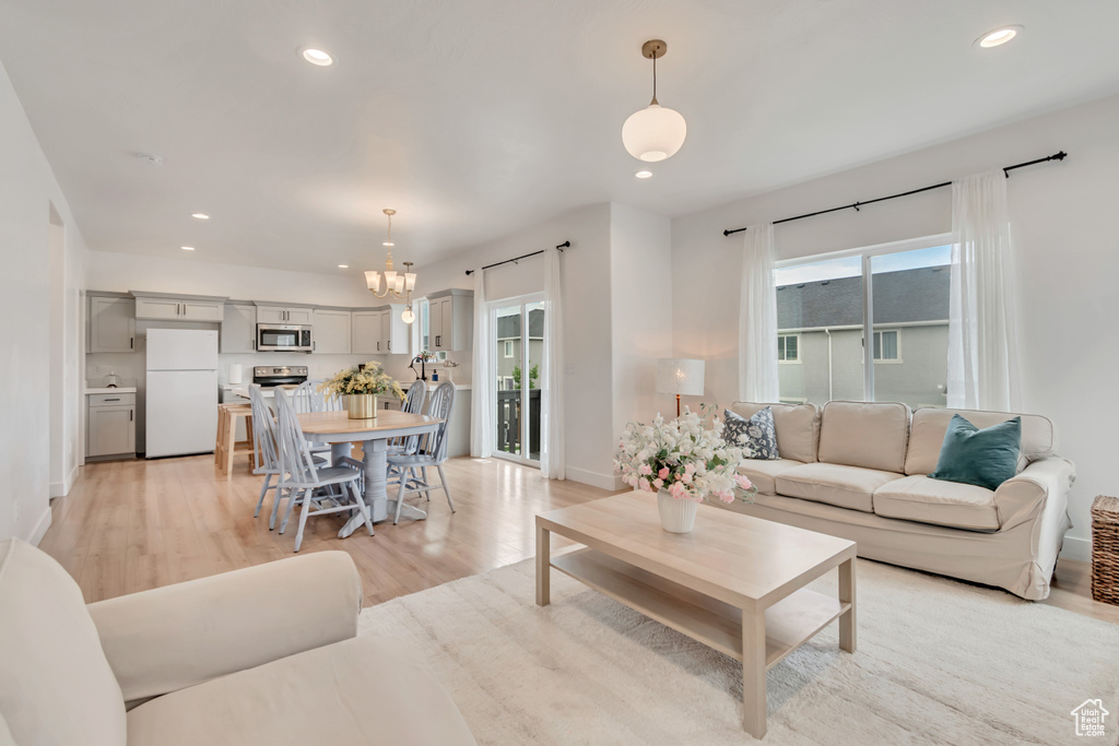 Living room with light wood finished floors, a chandelier, and recessed lighting