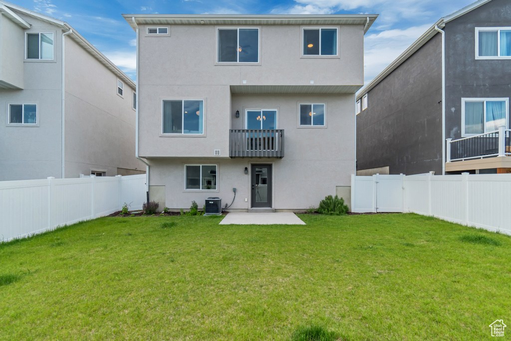 Rear view of house with a balcony, stucco siding, a patio area, and a fenced backyard