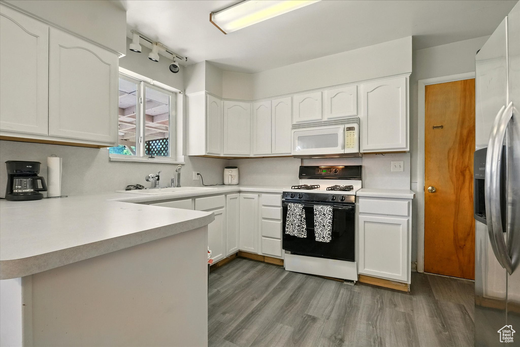 Kitchen featuring white appliances, wood finished floors, white cabinets, and light countertops