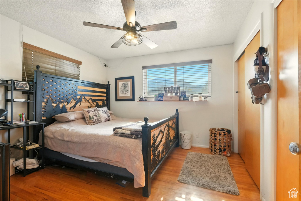 Bedroom with wood finished floors, a textured ceiling, and ceiling fan