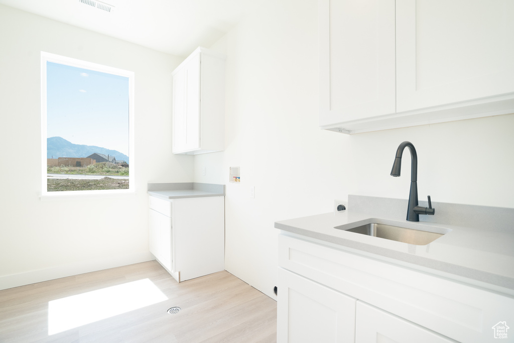 Laundry area featuring cabinet space, light wood-style flooring, washer hookup, and a mountain view