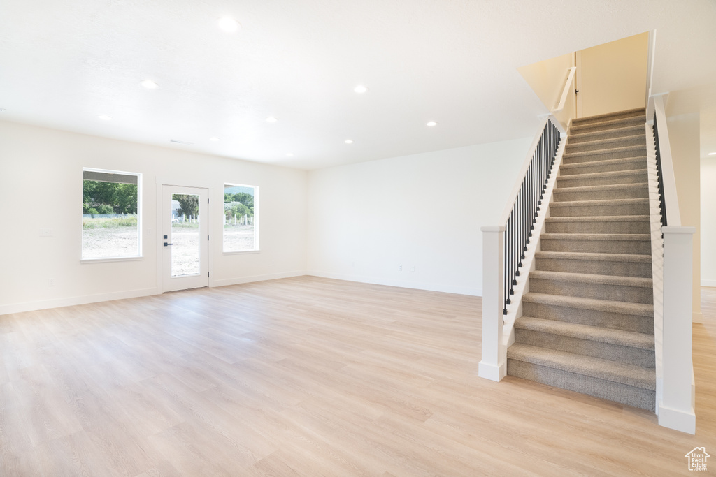 Unfurnished living room featuring stairway, recessed lighting, and light wood-style flooring