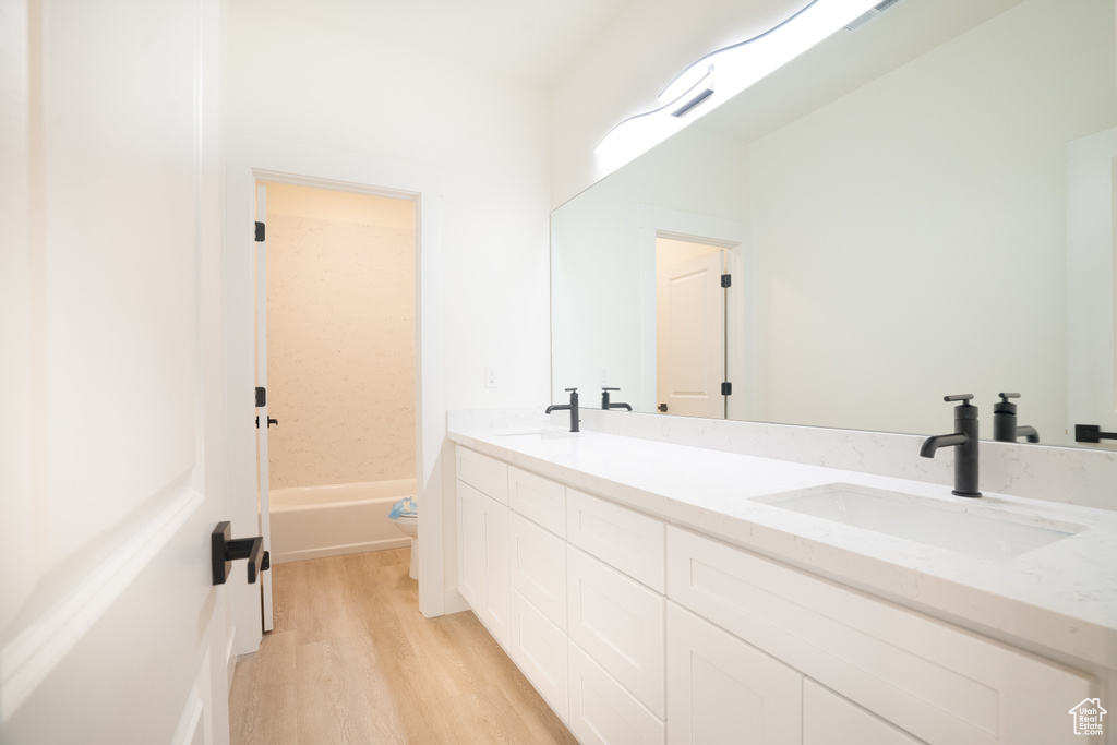 Full bathroom featuring double vanity and wood finished floors