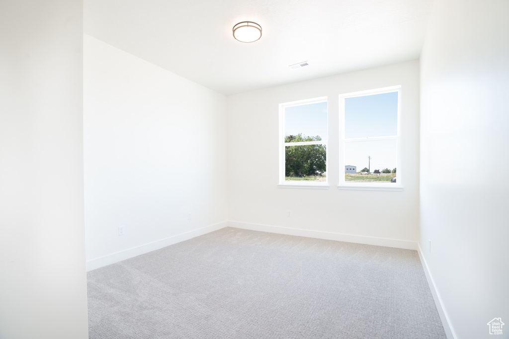Empty room featuring light colored carpet and baseboards