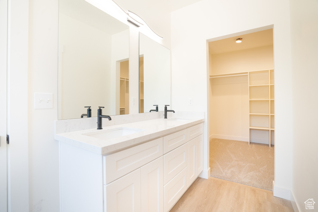 Bathroom featuring double vanity, wood finished floors, and a walk in closet
