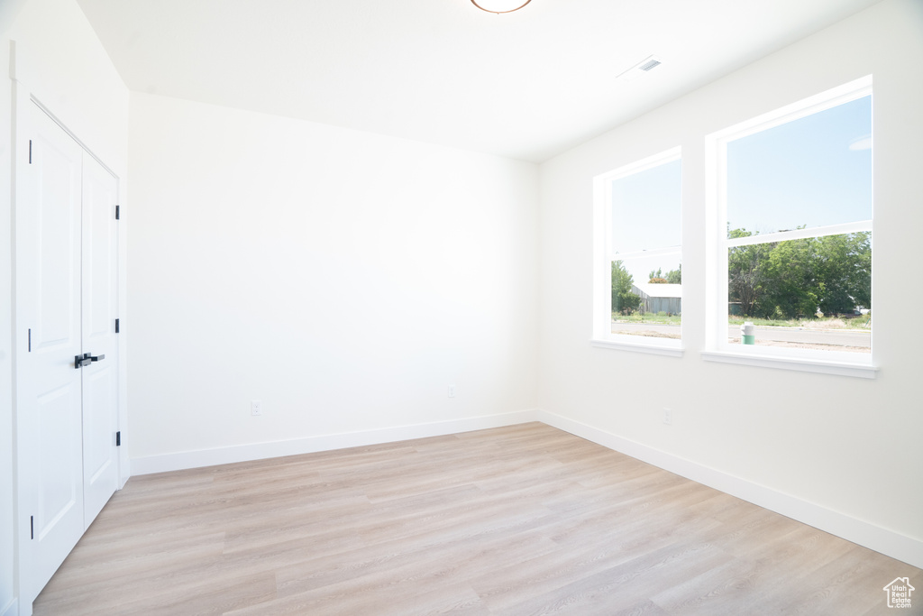 Unfurnished room featuring light wood finished floors and baseboards