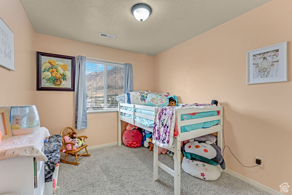 Carpeted bedroom with baseboards and a textured ceiling