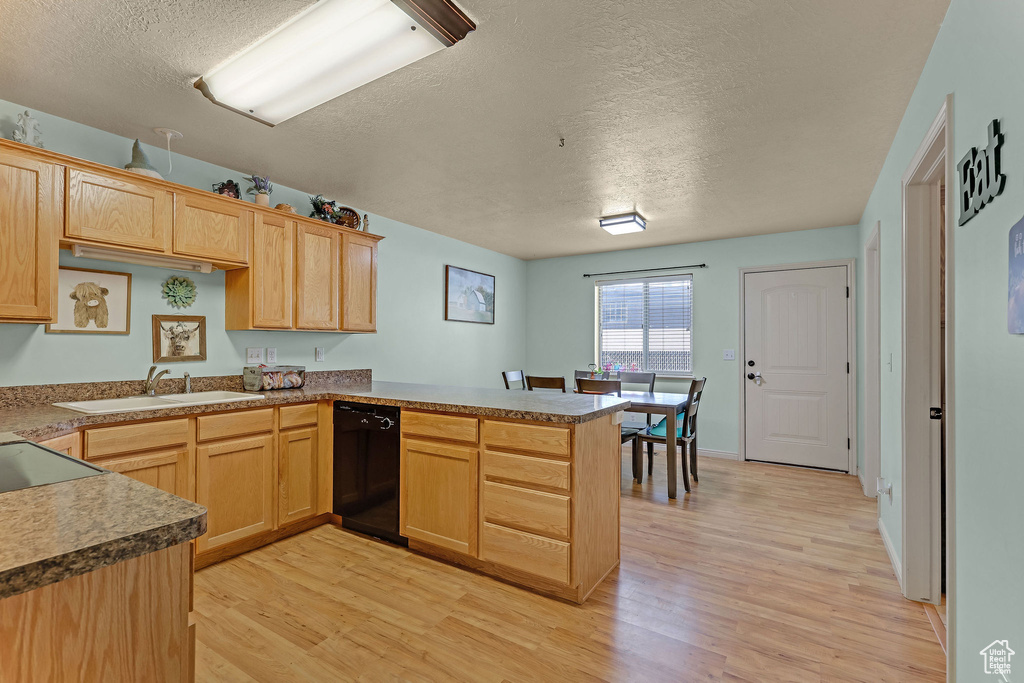 Kitchen with black dishwasher, a textured ceiling, a peninsula, light wood finished floors, and light brown cabinetry