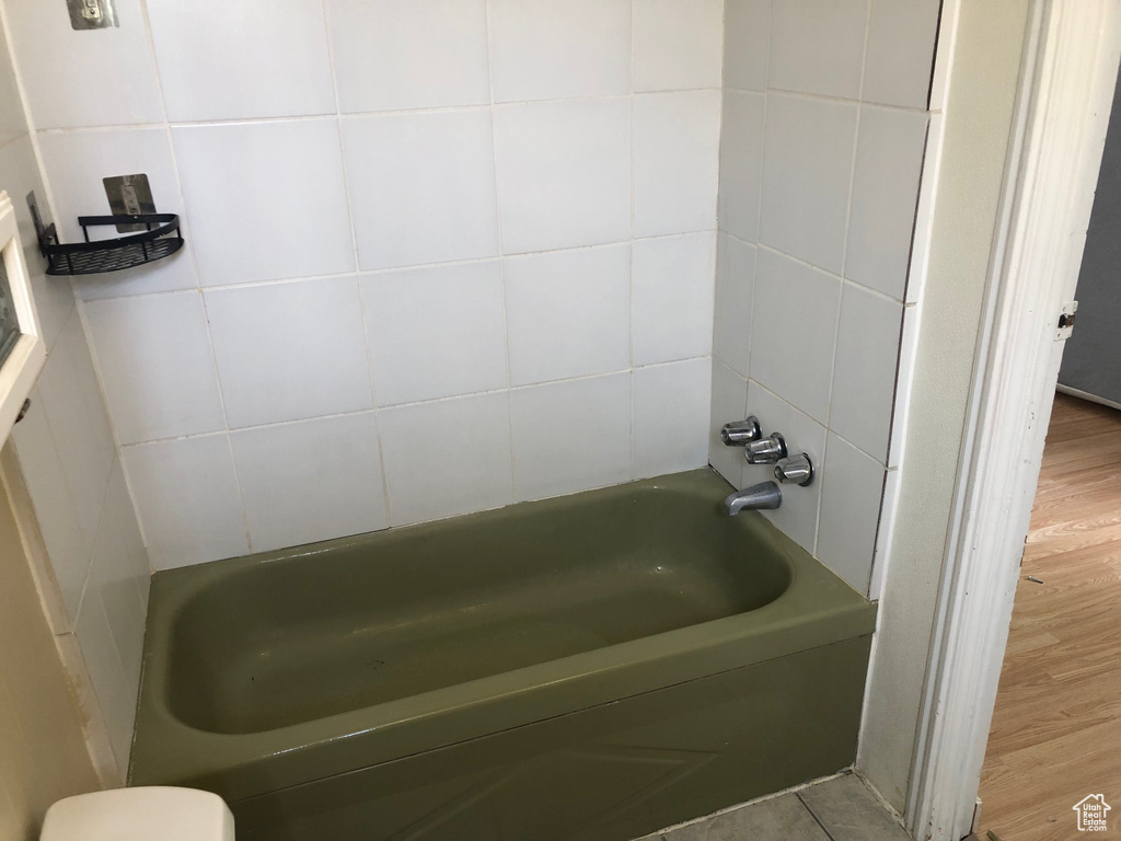 Full bath featuring wood finished floors, tile walls, and  shower combination