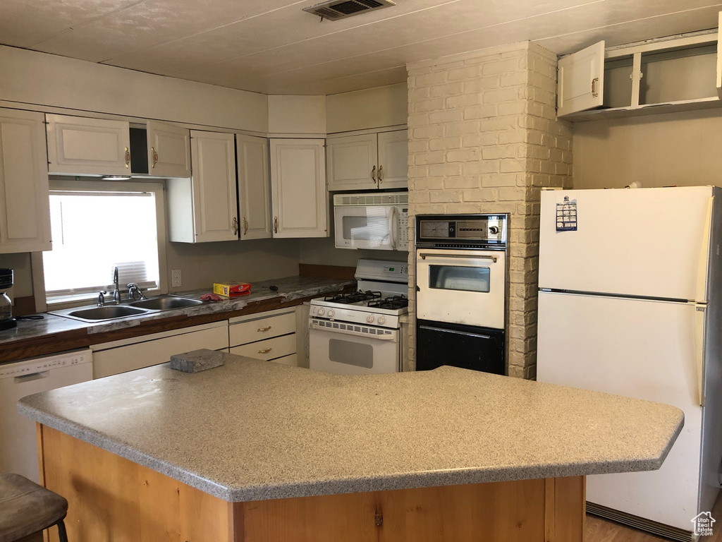 Kitchen with white appliances, a kitchen island, and light wood finished floors