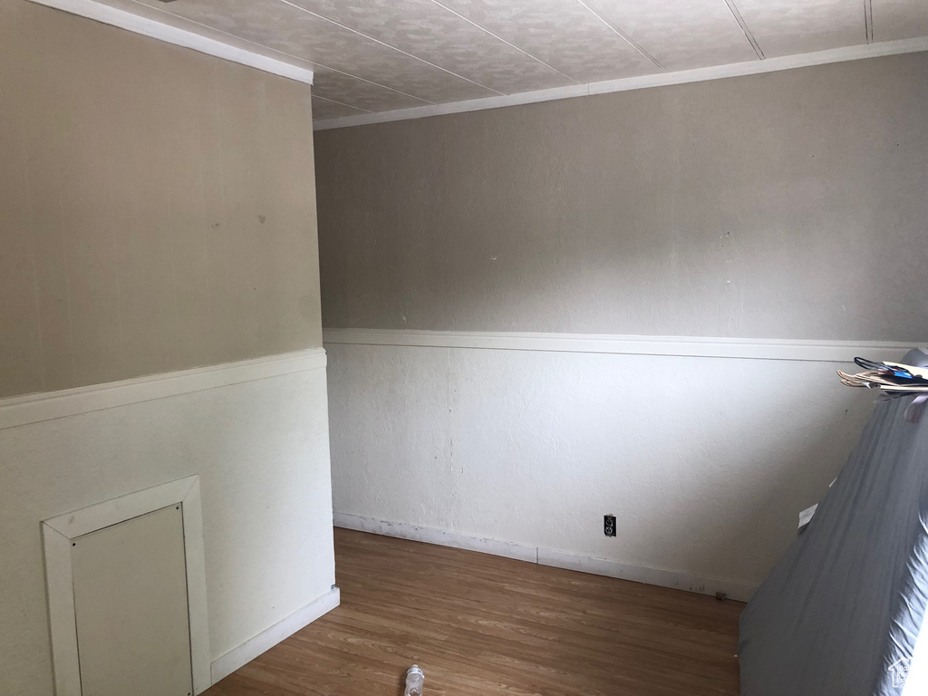 Empty room featuring wood finished floors and ornamental molding