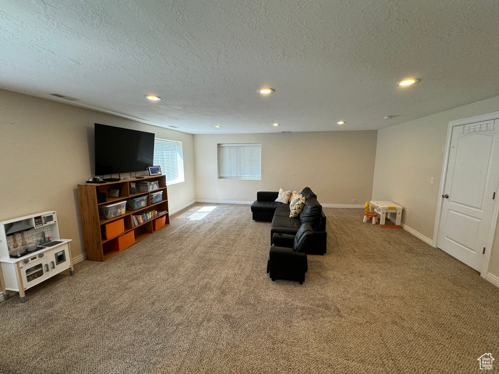 Living area with carpet flooring, a textured ceiling, and recessed lighting