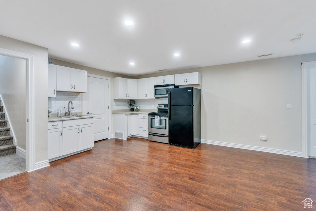 Kitchen with stainless steel appliances, light countertops, backsplash, dark wood-style floors, and recessed lighting