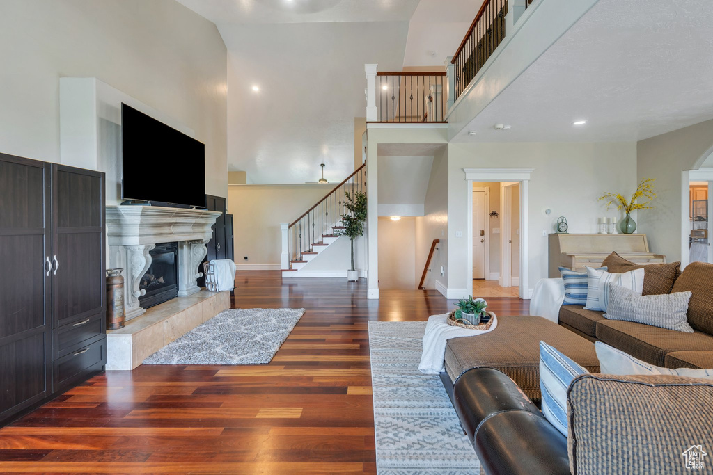 Living area with stairs, a high ceiling, a fireplace, wood finished floors, and arched walkways