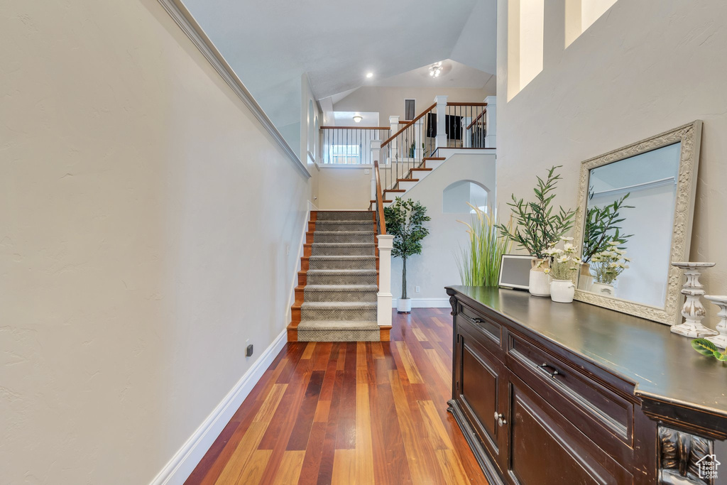 Entryway with dark wood-type flooring, stairway, and a high ceiling