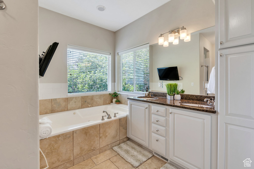 Bathroom with a bath, double vanity, and tile patterned flooring