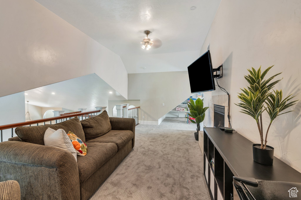 Living room with light colored carpet, ceiling fan, and vaulted ceiling