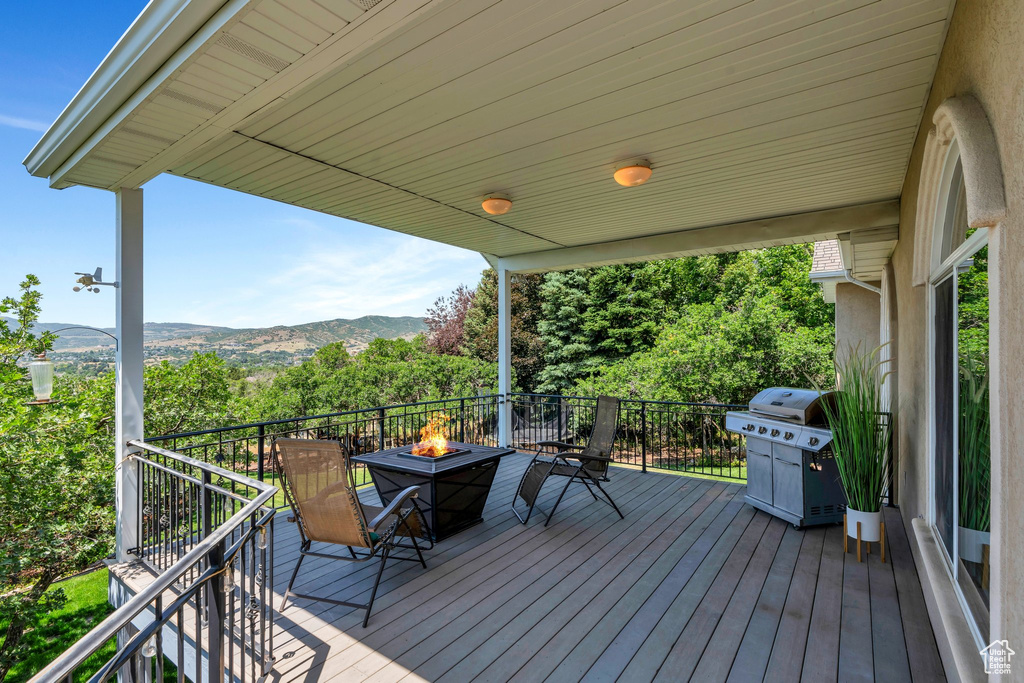Wooden deck with an outdoor fire pit, area for grilling, and a mountain view