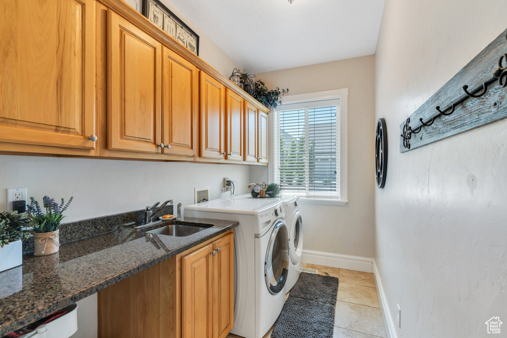 Laundry area with cabinet space, washing machine and dryer, and light tile patterned floors
