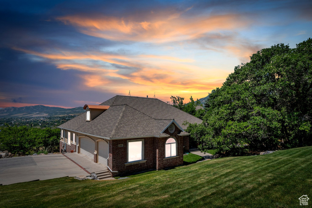 View of property exterior with brick siding, driveway, a garage, and a yard