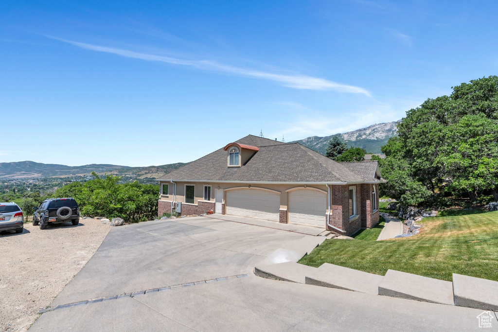 View of front of house with brick siding, a front yard, a mountain view, and a garage