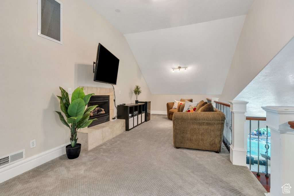 Living room featuring lofted ceiling, a fireplace, and carpet floors