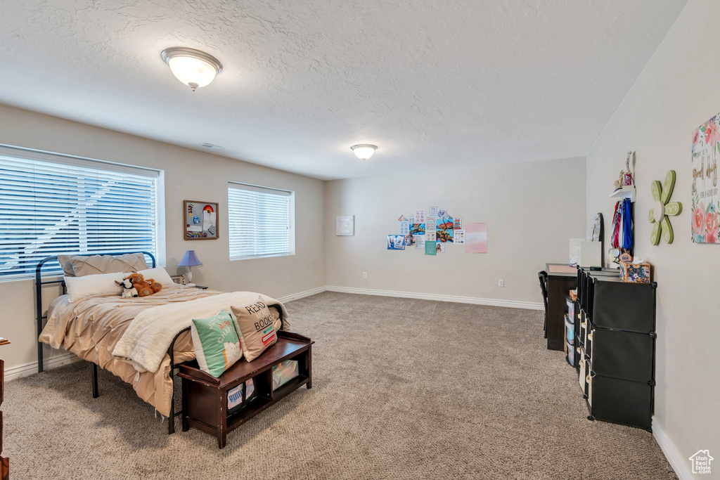 Bedroom with light colored carpet and a textured ceiling