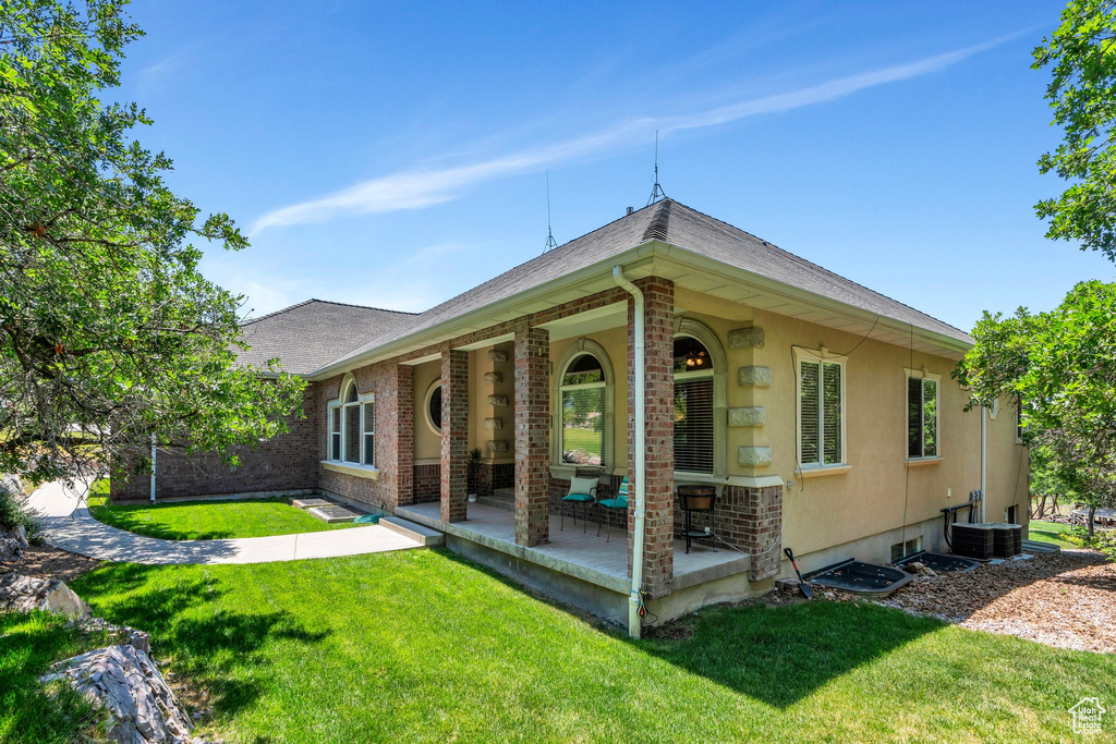 Rear view of property with a yard, brick siding, and roof with shingles