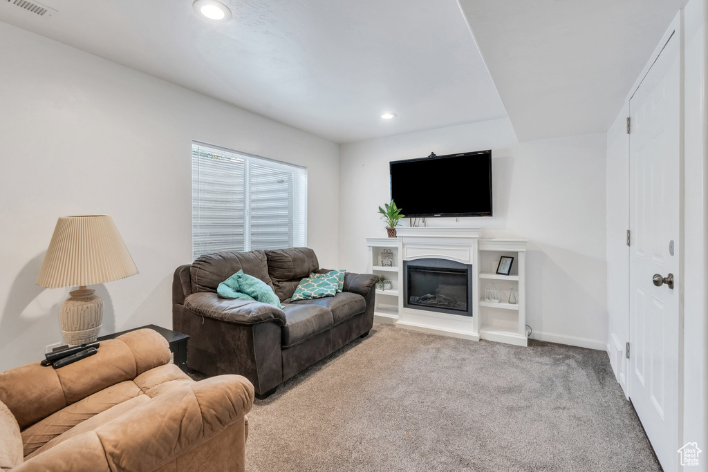 Carpeted living area featuring recessed lighting and a glass covered fireplace
