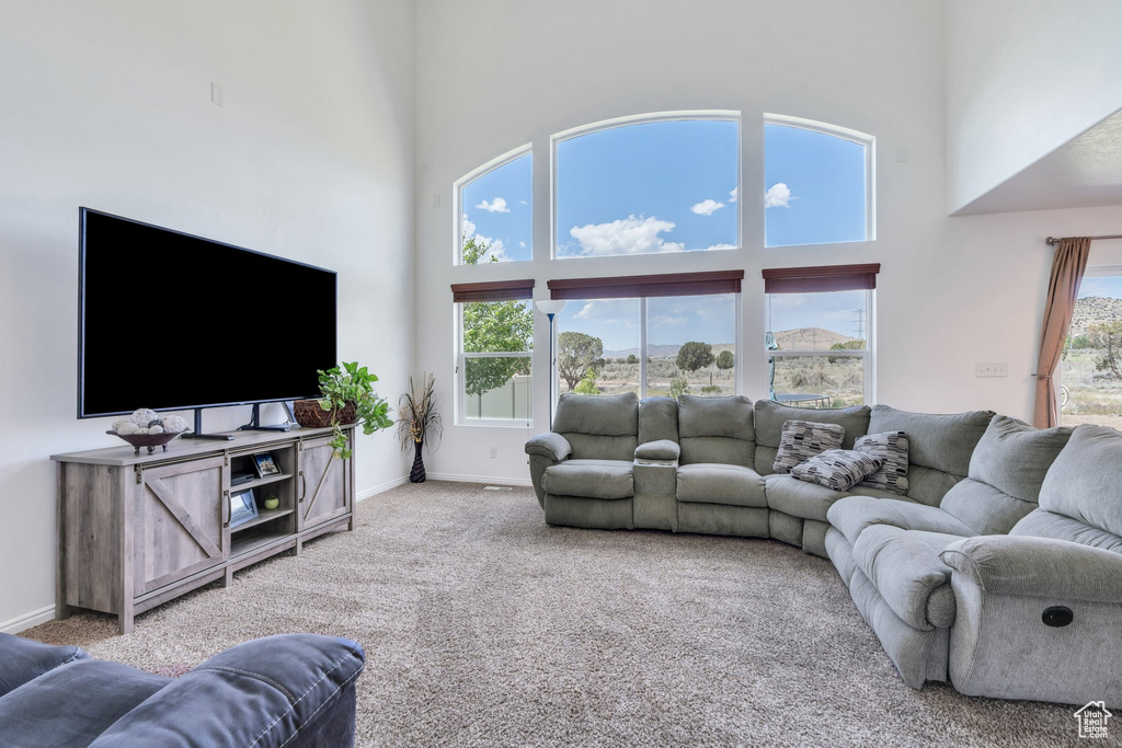 Carpeted living area with a towering ceiling and baseboards