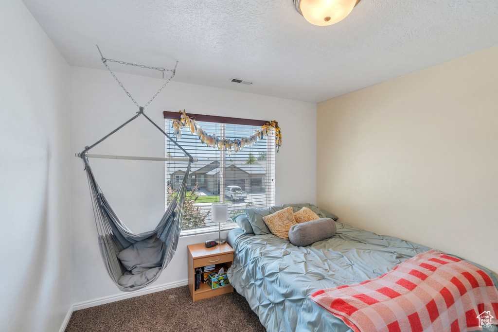 Carpeted bedroom with a textured ceiling and baseboards