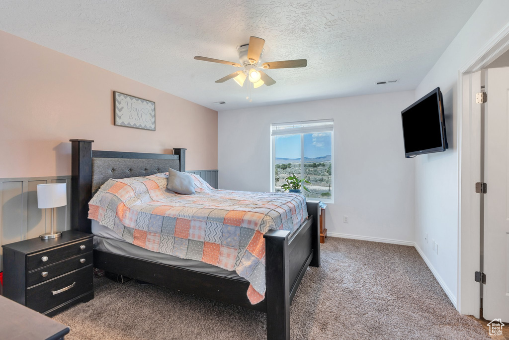 Bedroom with carpet, ceiling fan, and a textured ceiling