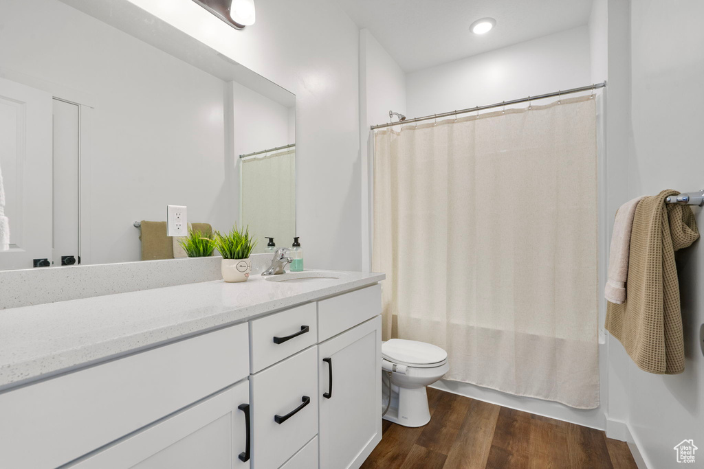 Full bath featuring vanity, wood finished floors, and shower / bath combination with curtain