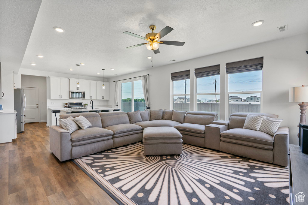Living room with dark wood finished floors, recessed lighting, ceiling fan, and a textured ceiling