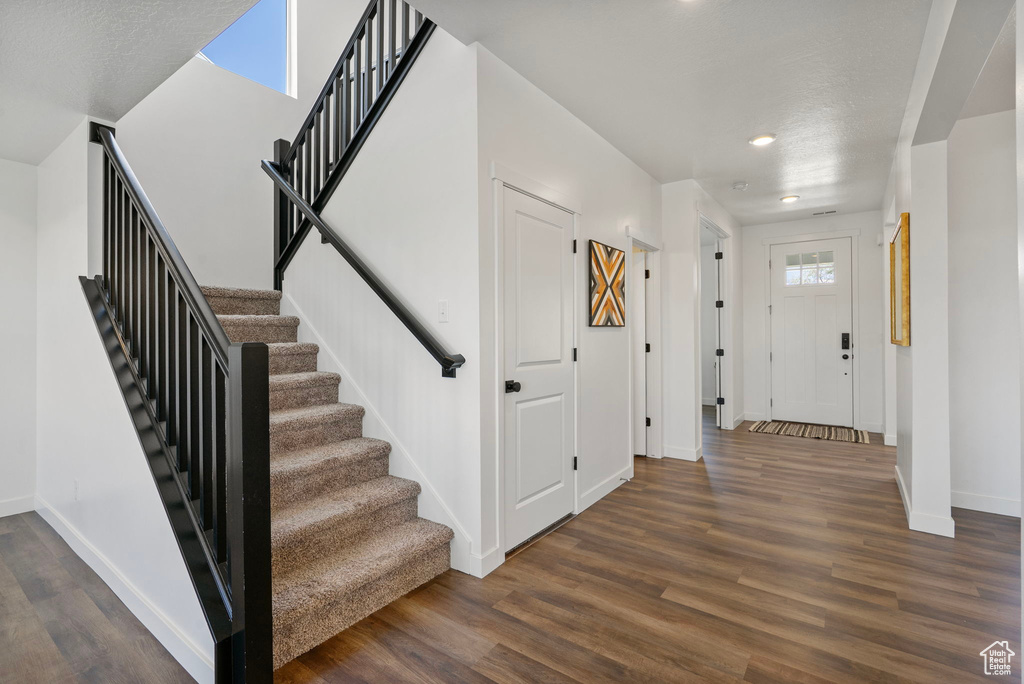 Foyer entrance featuring dark wood-style flooring, recessed lighting, and stairway