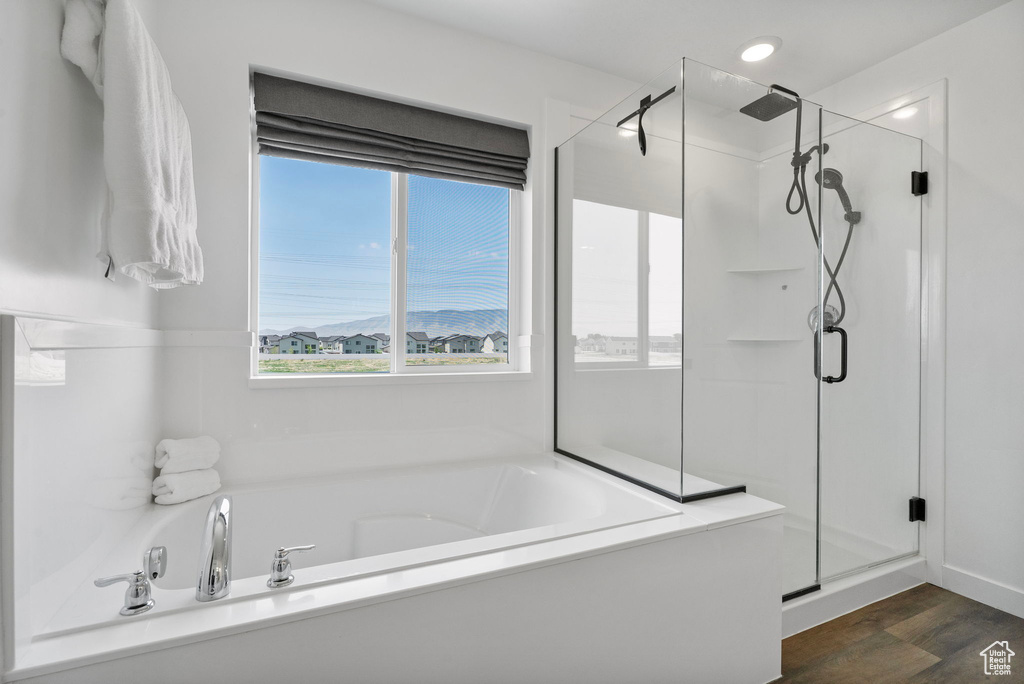 Full bathroom featuring a shower stall, a garden tub, and wood finished floors