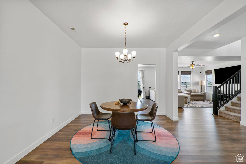 Dining area featuring a chandelier, wood finished floors, stairs, and ceiling fan