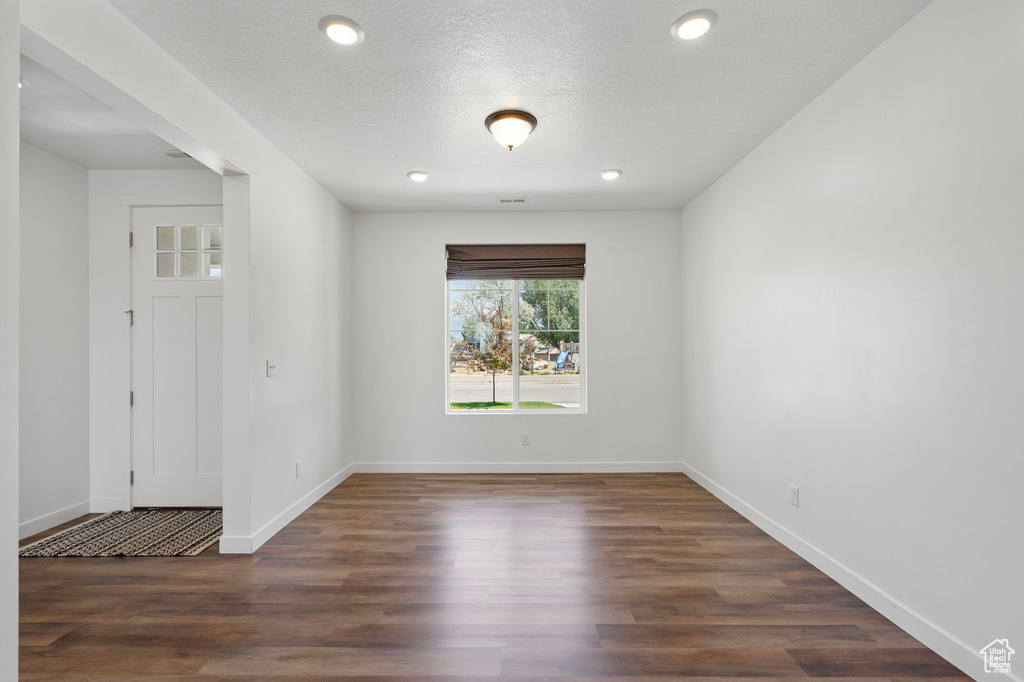 Empty room with dark wood-style flooring and recessed lighting